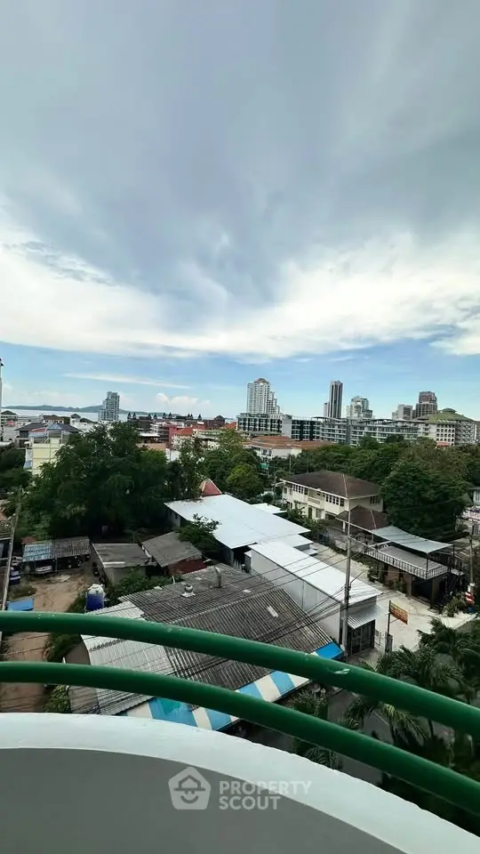 Stunning cityscape view from a high-rise balcony showcasing urban skyline and lush greenery.