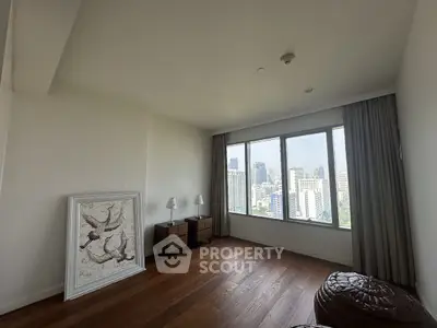 Spacious room with city view and elegant decor, featuring large windows and wooden flooring.