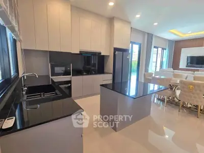 Luxurious modern kitchen with sleek black countertops and open layout, adjacent to elegant dining area.