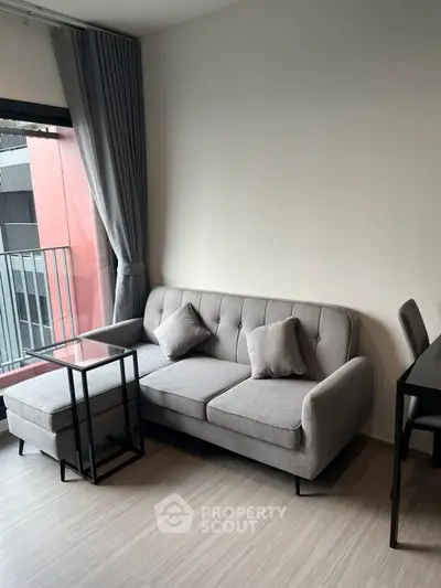 Modern living room with stylish gray sofa and floor-to-ceiling window view.