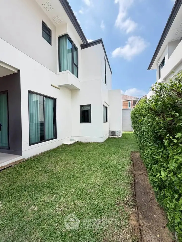 Modern two-story house with lush green lawn and contemporary design.