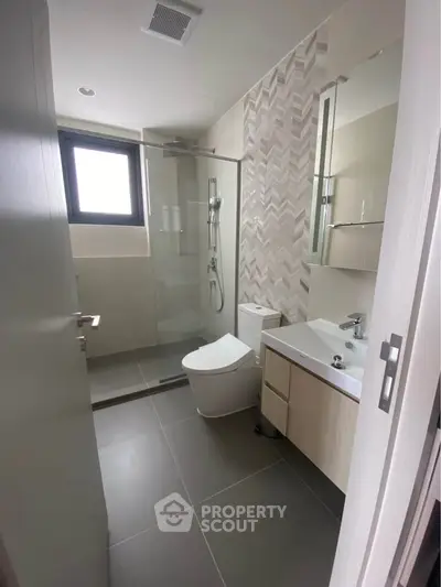 Modern bathroom with sleek design, featuring a glass shower enclosure and contemporary fixtures.