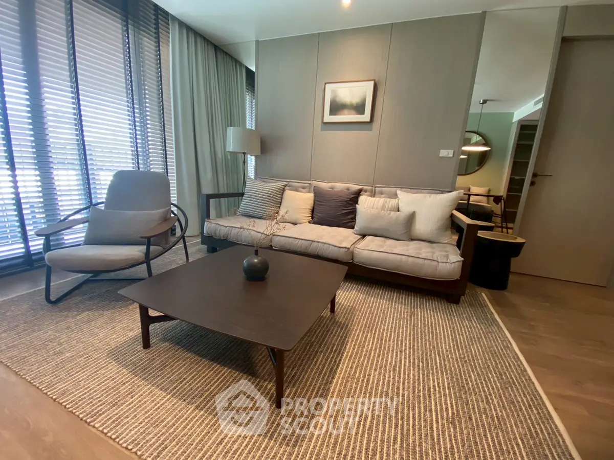 Modern living room with stylish furniture and natural light through large windows.