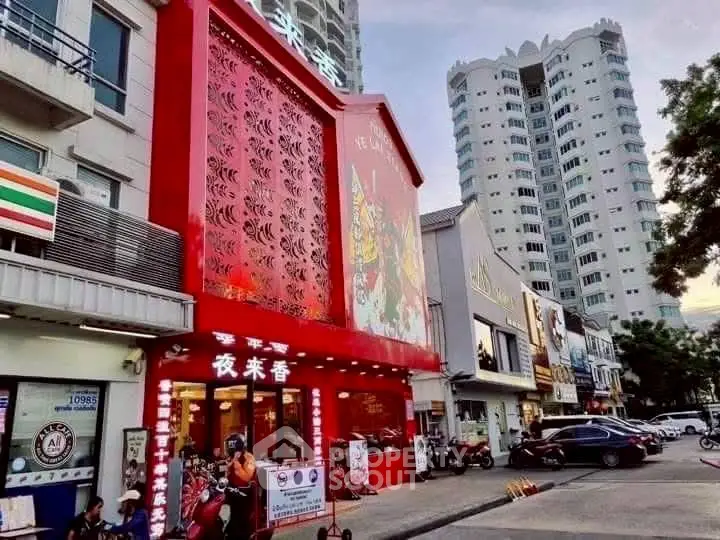 Vibrant street view with red facade building and high-rise apartments.