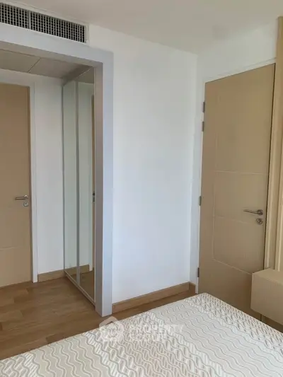 Modern bedroom with wooden flooring and mirrored wardrobe in a minimalist design.