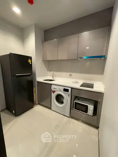 Modern compact kitchen with appliances including fridge, washing machine, and microwave.