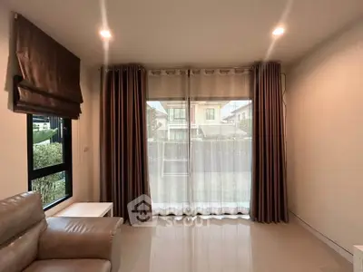 Spacious living room with large windows and elegant curtains in a modern home.