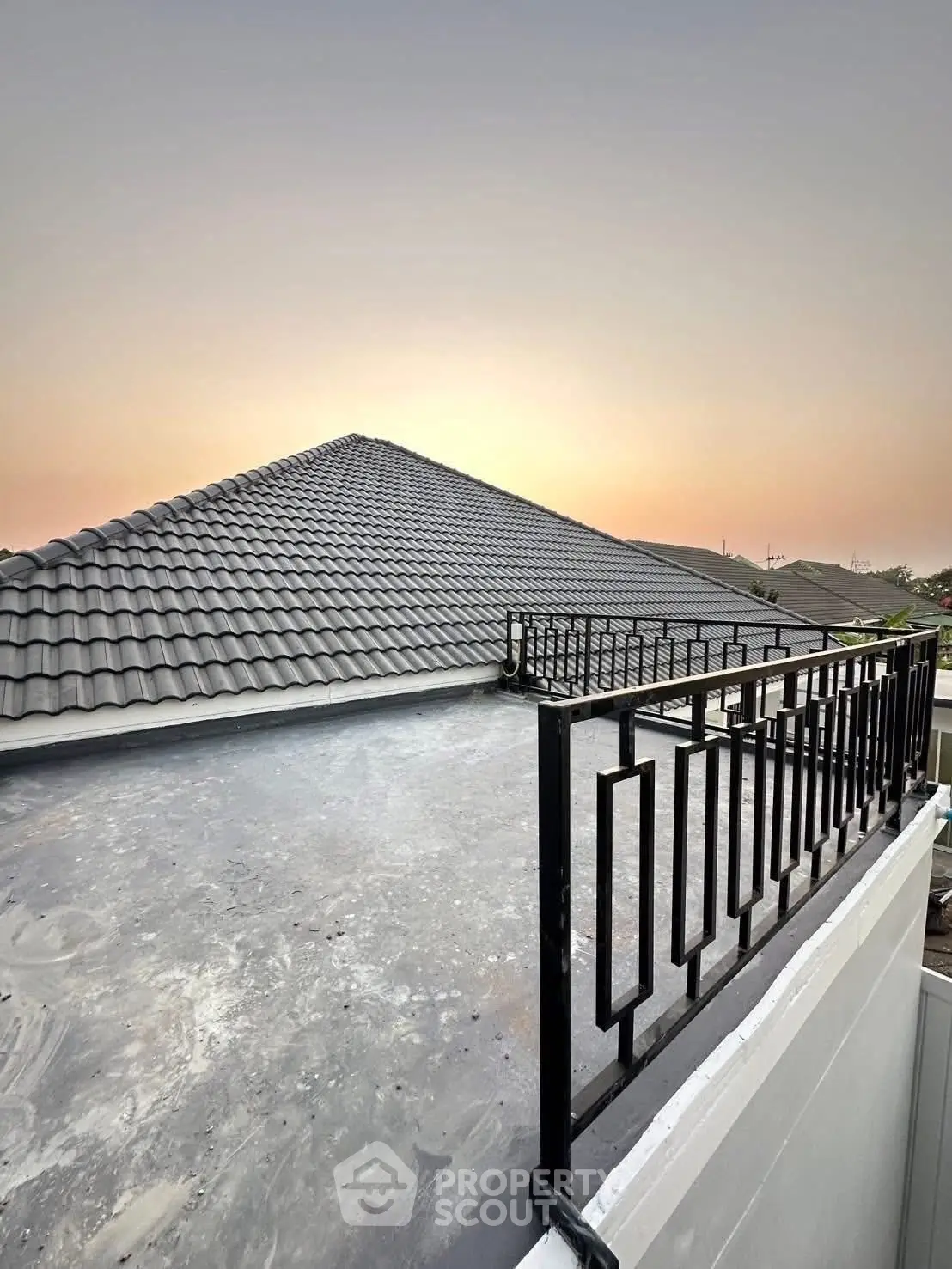 Modern rooftop with sleek railing and sunset view, perfect for urban living.