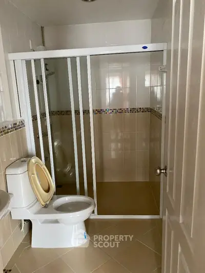 Spacious bathroom with full walk-in shower, modern tiling, and essential fixtures, offering a clean and functional space.