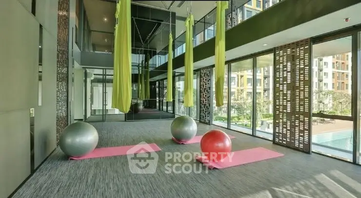 Modern gym with aerial yoga setup and pool view in luxury apartment complex.