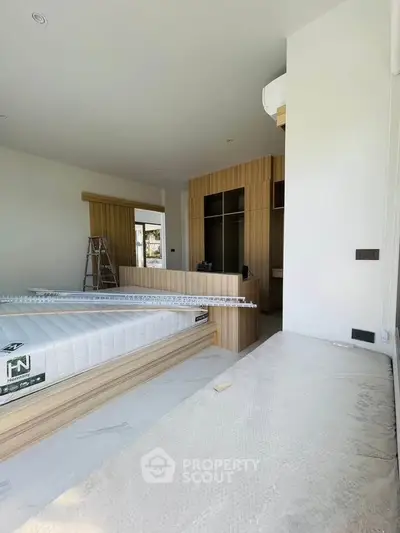 Spacious bedroom under renovation with modern wooden accents and natural light.