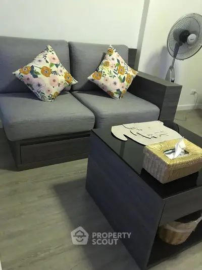 Cozy living room with modern gray sofa and floral cushions, featuring a stylish black coffee table.