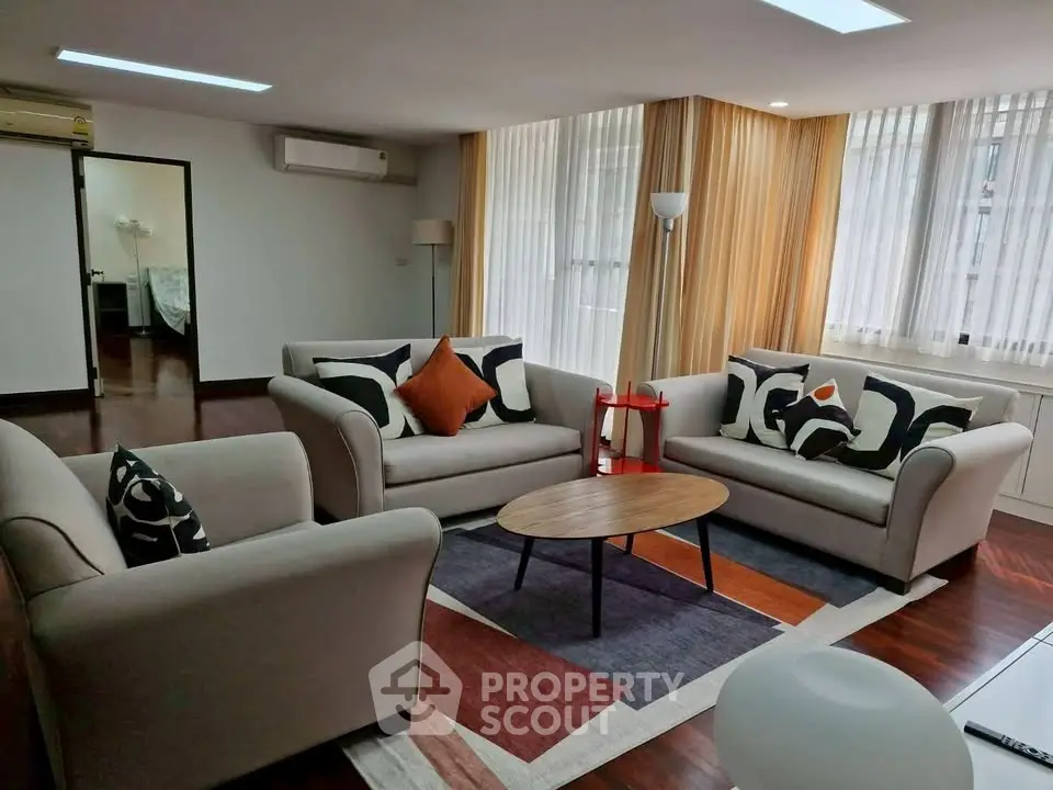 Spacious living room with modern furniture and large windows in a stylish apartment.