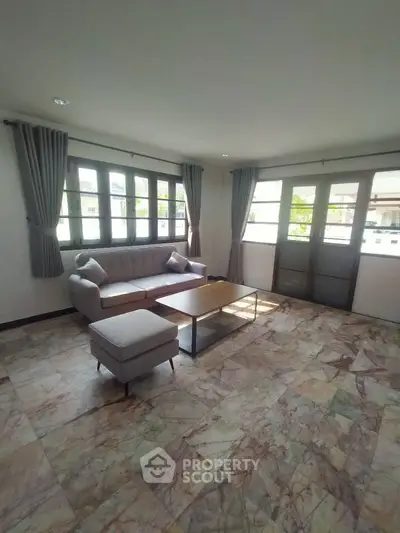 Spacious living room with elegant marble flooring and large windows for natural light.