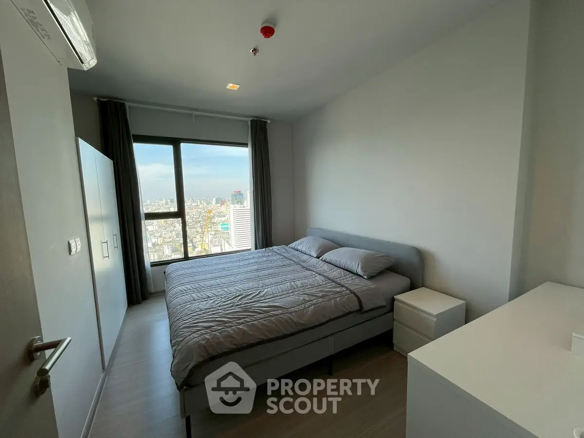Modern bedroom with city view, featuring a comfortable bed and sleek furnishings.