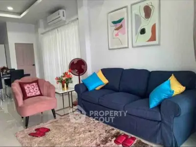 Stylish living room with modern decor, featuring a plush blue sofa, colorful cushions, and elegant wall art.