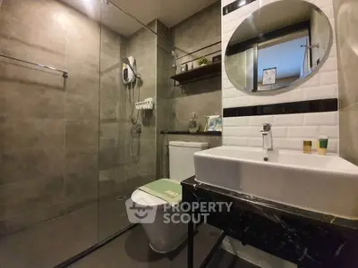 Modern bathroom with glass shower, sleek sink, and stylish tiles.