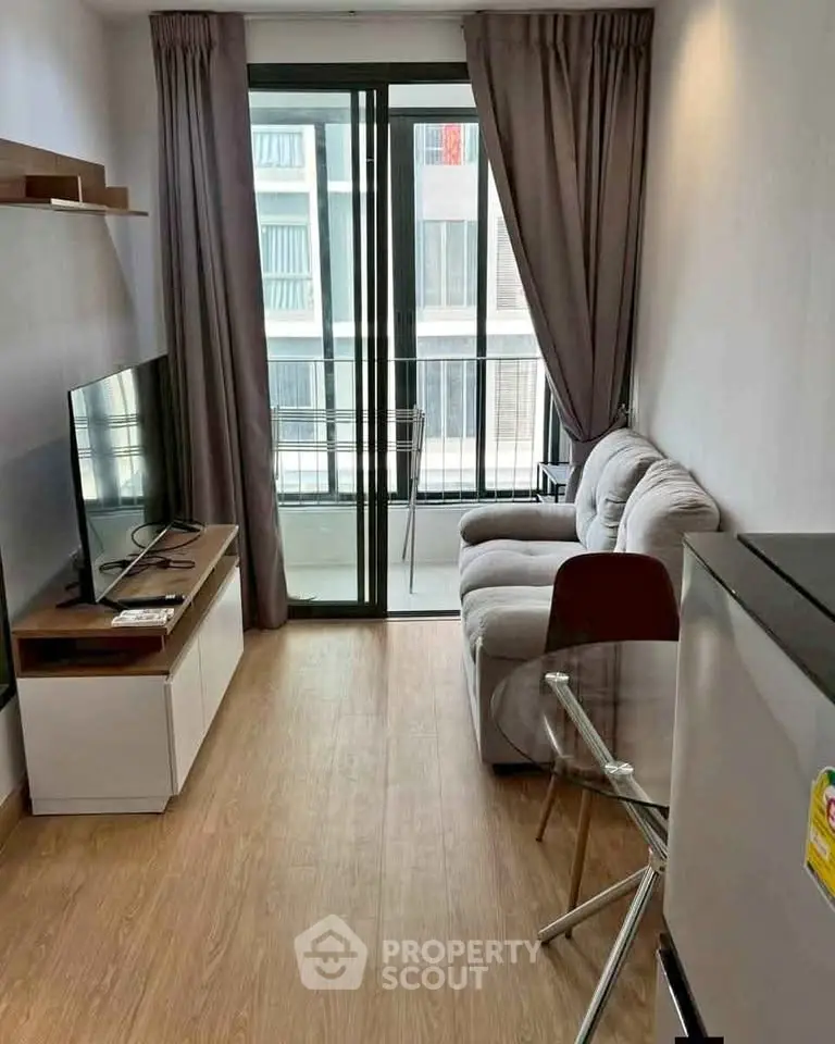 Modern living room with balcony view, featuring sleek furniture and natural light.