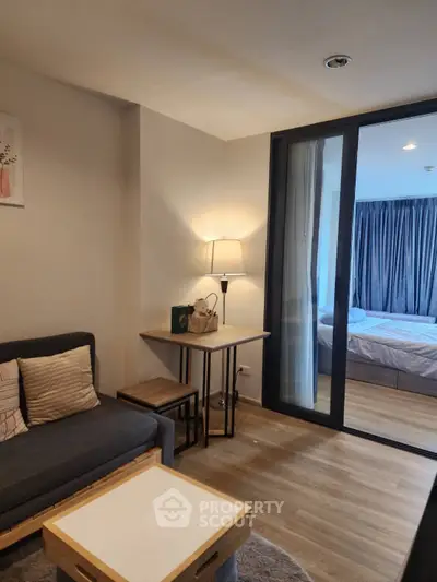 Modern living room with cozy seating and view into a stylish bedroom