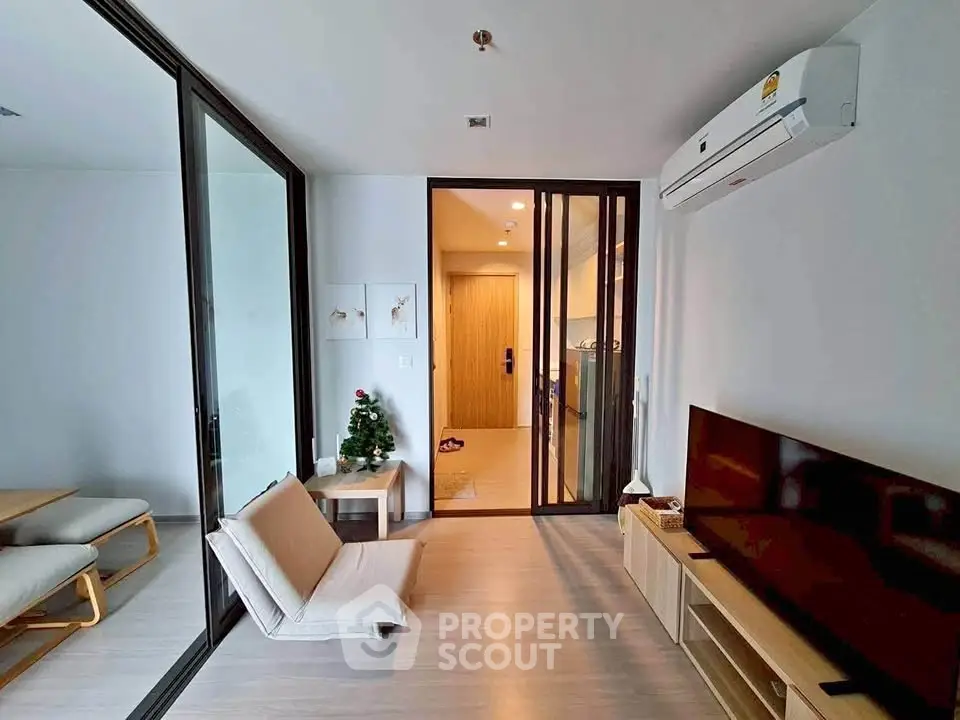 Modern living room with sleek design, featuring a TV, air conditioning, and stylish furniture in a cozy apartment.