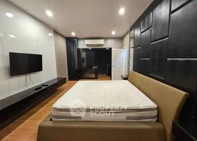 Luxurious bedroom with modern design, featuring a sleek TV setup and stylish wall paneling.