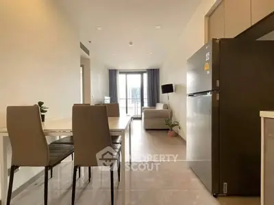 Modern open-plan living room with dining area and kitchen, featuring sleek furniture and natural light.