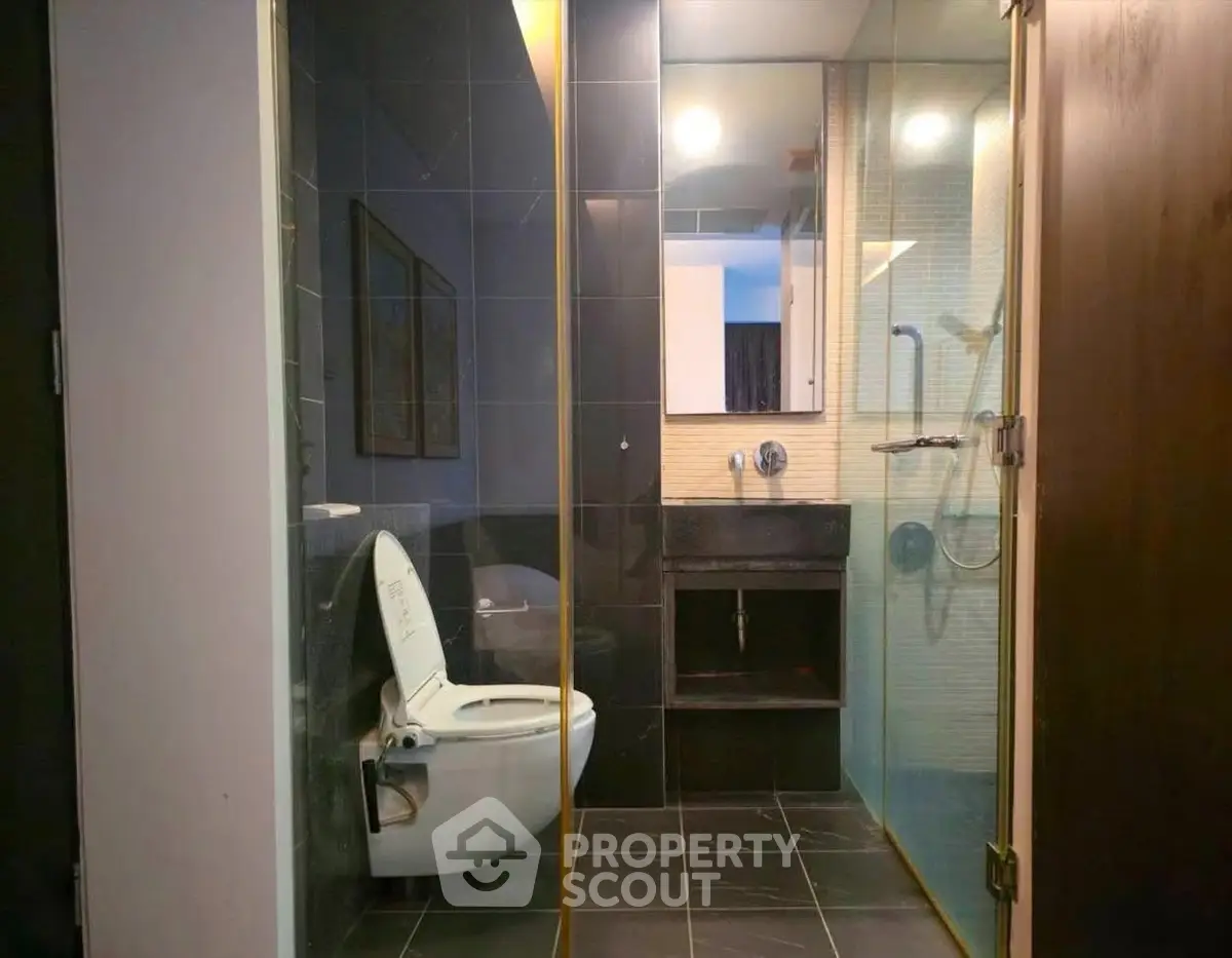 Modern bathroom with sleek black tiles and glass shower enclosure