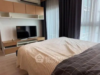 Modern bedroom with cozy bedding, TV, and ample natural light from large windows.