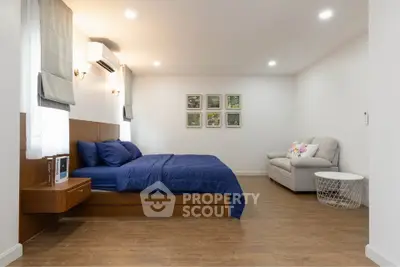 Spacious bedroom with modern decor and cozy seating area.