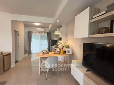 Modern living room with stylish decor and open layout, featuring a cozy dining area and large TV.