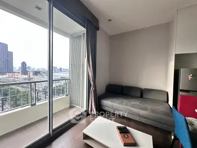 Modern living room with balcony and city view, featuring sleek furniture and large windows for natural light.