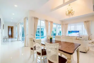 Spacious and elegant living room with chandelier and large windows offering a bright and airy atmosphere.