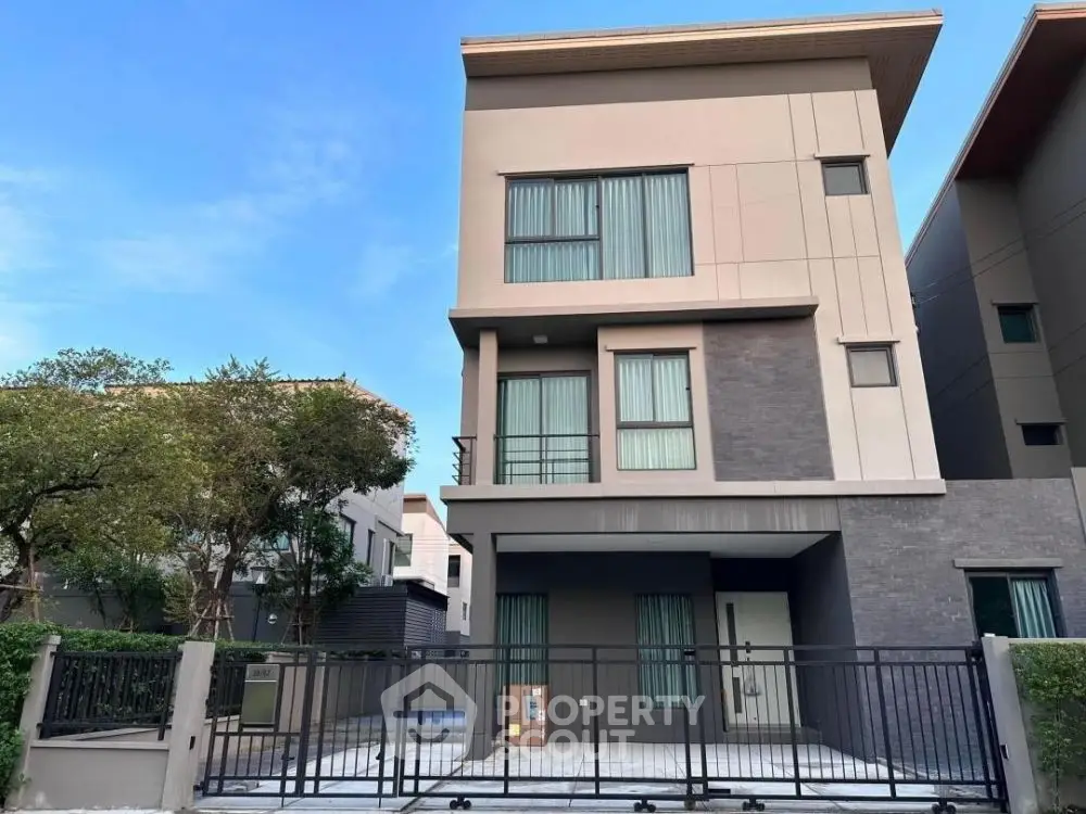 Modern three-story house with sleek design and gated entrance in a serene neighborhood.