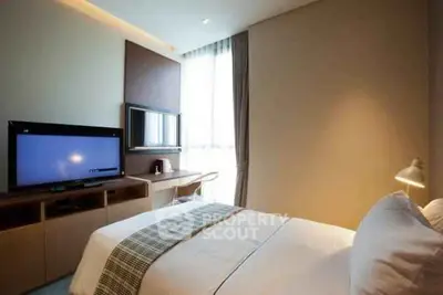 Cozy bedroom with modern decor, featuring a large window and flat-screen TV, perfect for relaxation.