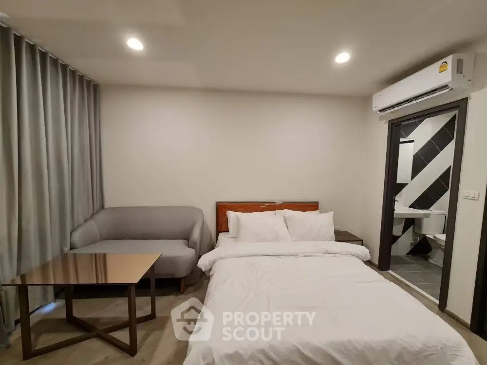 Modern bedroom with cozy bed, sofa, and air conditioning unit