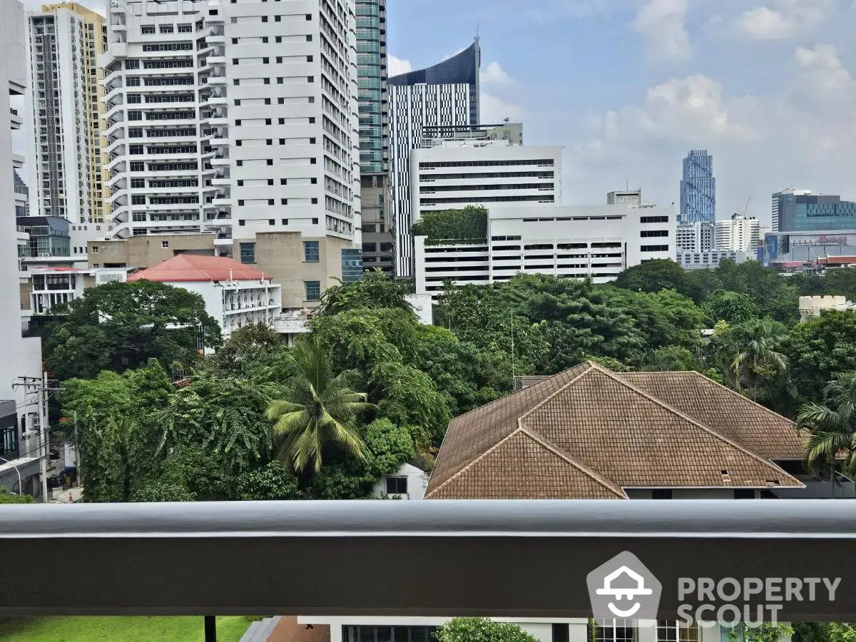 Stunning cityscape view from a modern balcony overlooking lush greenery and urban skyline.