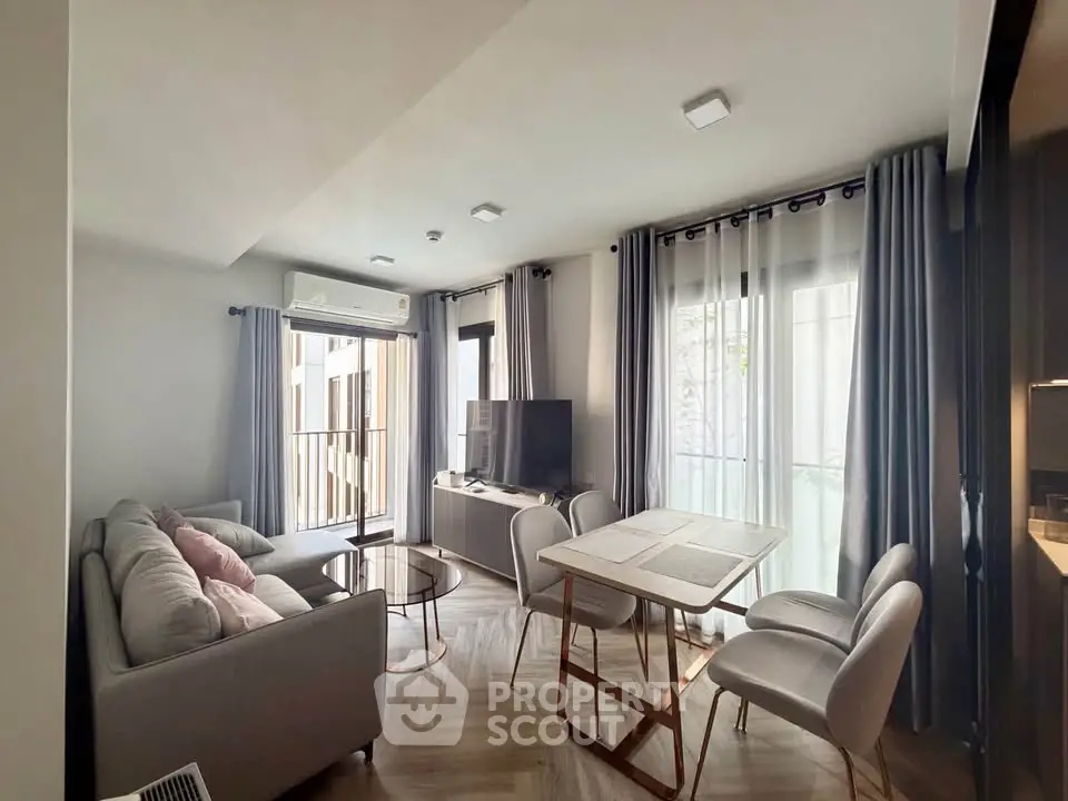 Modern living room with stylish furniture and natural light, featuring a cozy sofa and dining area.