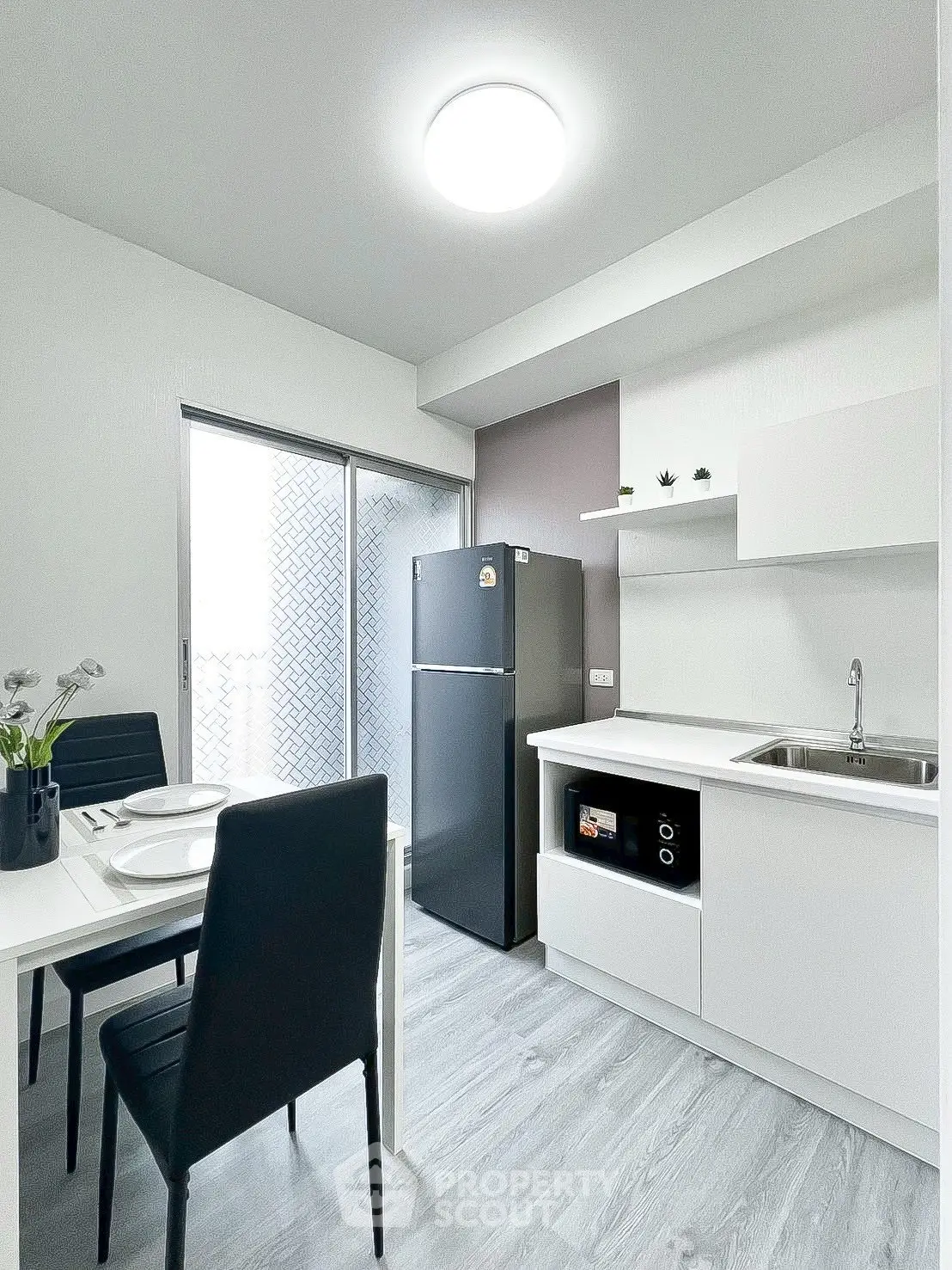 Modern kitchen with sleek design, featuring a dining area, fridge, and built-in oven, perfect for urban living.