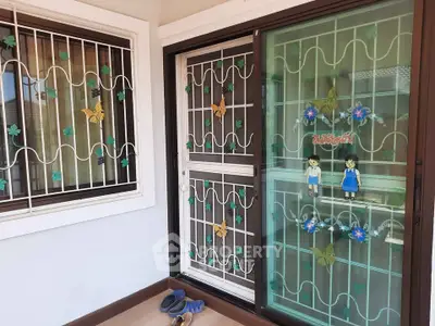 Charming balcony with decorative security grills and sliding glass doors in a cozy home setting.