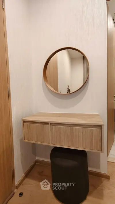 Modern minimalist vanity area with round mirror and wooden drawers in stylish home interior.