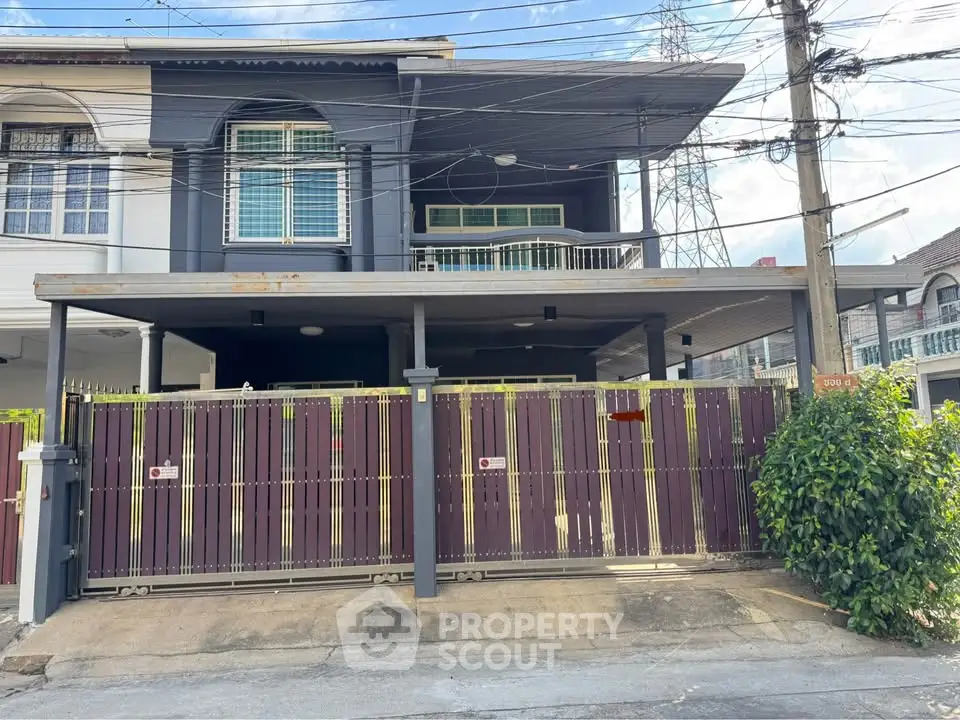 Modern two-story house with gated entrance and spacious balcony.