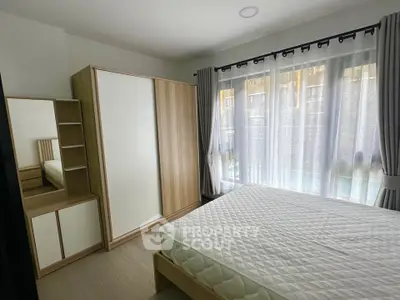 Modern bedroom with large window, stylish wardrobe, and cozy bed in a bright, inviting space.