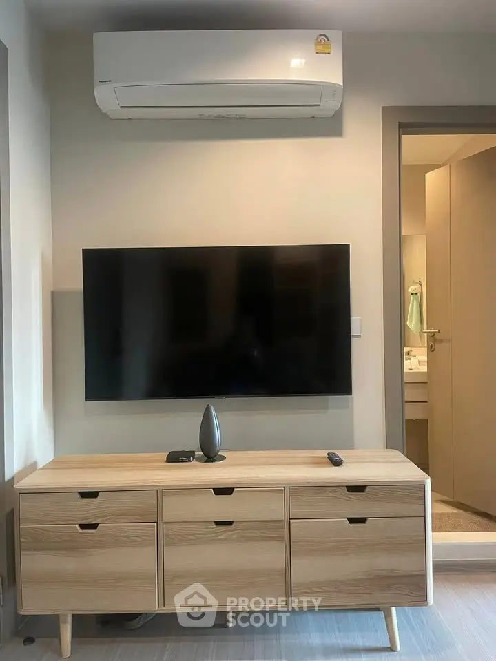 Modern living room with sleek TV setup and air conditioning unit, showcasing minimalist furniture design.