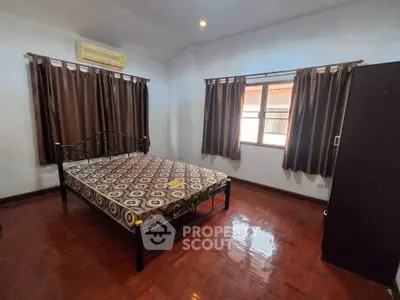 Spacious bedroom with wooden flooring and natural light