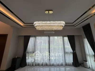 Elegant living room with chandelier and large windows, featuring modern curtains and ambient lighting.