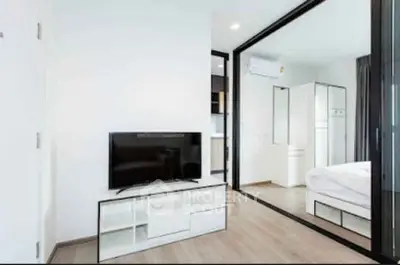 Modern apartment interior with sleek TV stand and mirrored bedroom view.