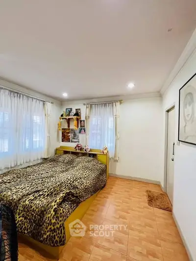 Cozy bedroom with leopard print bedding and wooden flooring, perfect for relaxation.