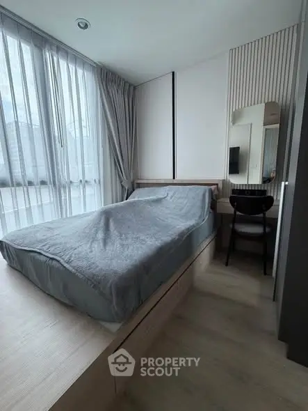 Modern bedroom with sleek design and natural light, featuring a cozy bed and stylish decor.