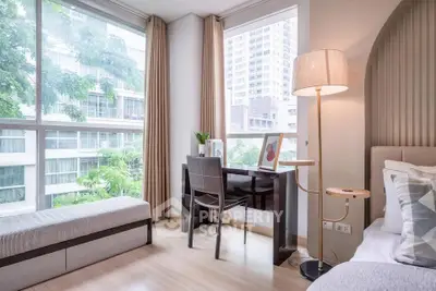 Bright and modern bedroom with study area and large windows overlooking city view.