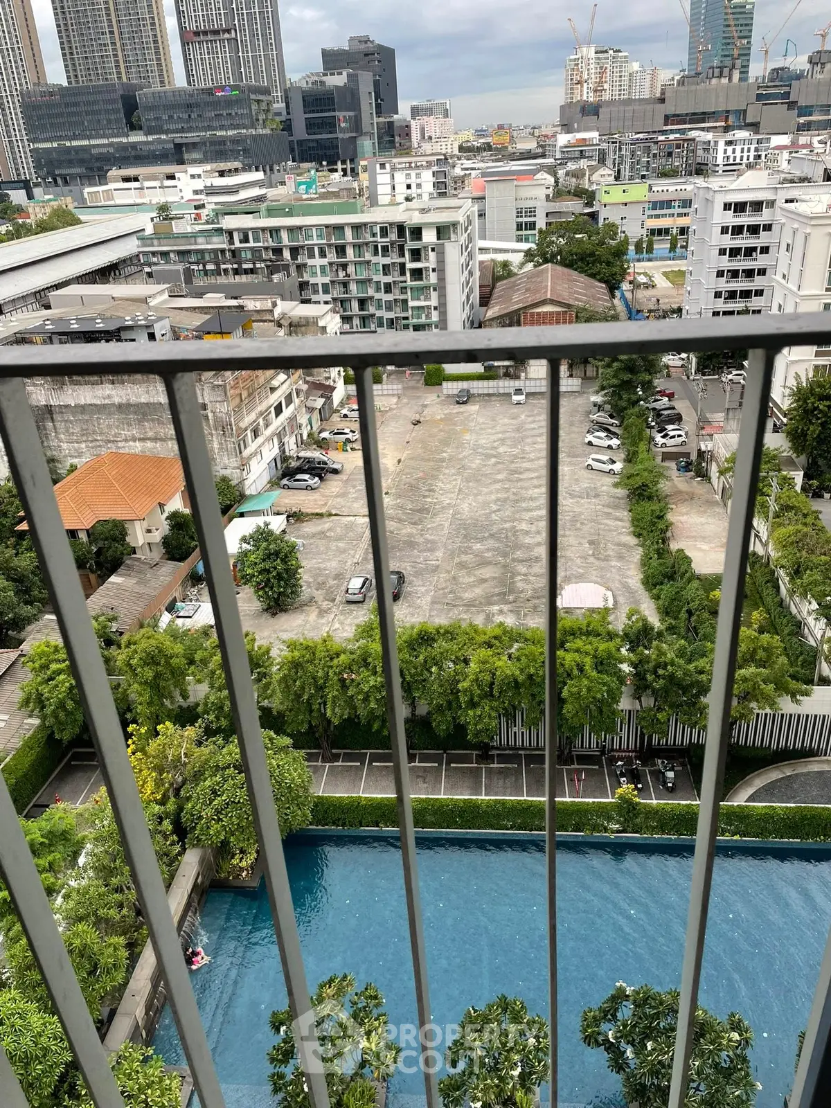 Stunning city view from high-rise balcony overlooking pool and urban landscape.